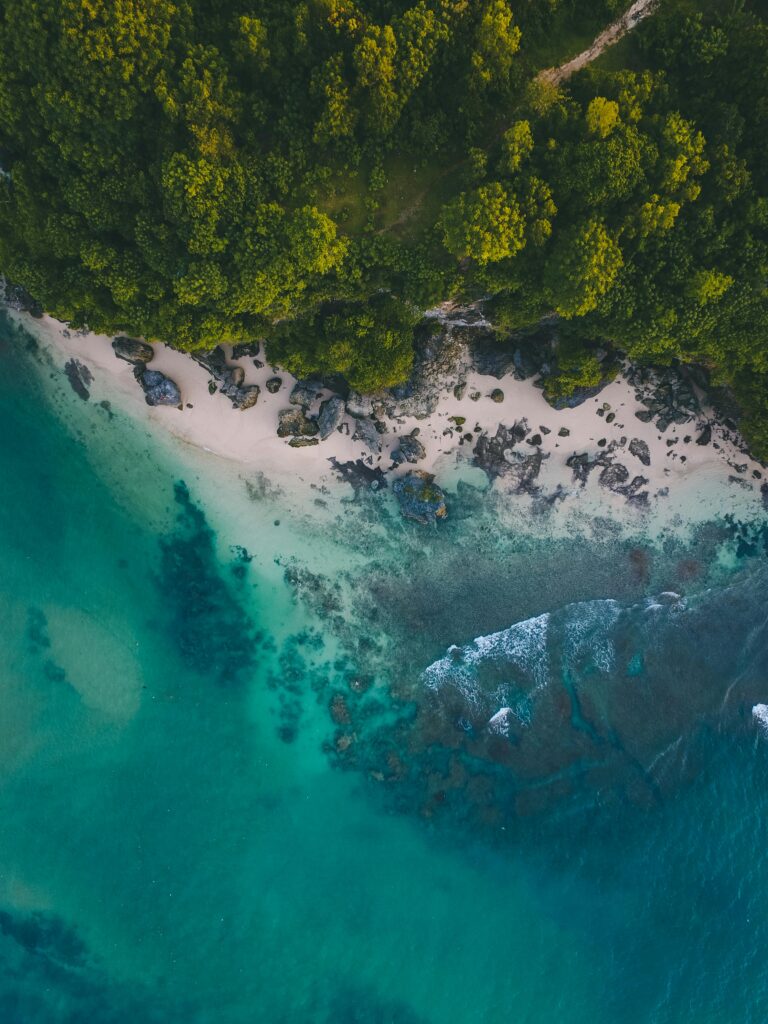 Stunning aerial view of a pristine beach in Bali with turquoise waters and lush greenery.